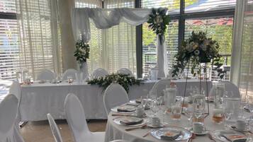A banquet hall with round tables set for a formal event, featuring white tablecloths, chairs, and floral centerpieces.