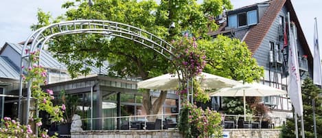 Ein Restaurant mit Außenbereich, Steinwänden und einem Metallbogen.