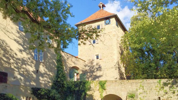Un edificio histórico de piedra con ventanas de arco y una torre.
