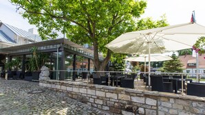 Un patio al aire libre con suelo de piedra, mobiliario exterior y una gran sombrilla que proporciona sombra.