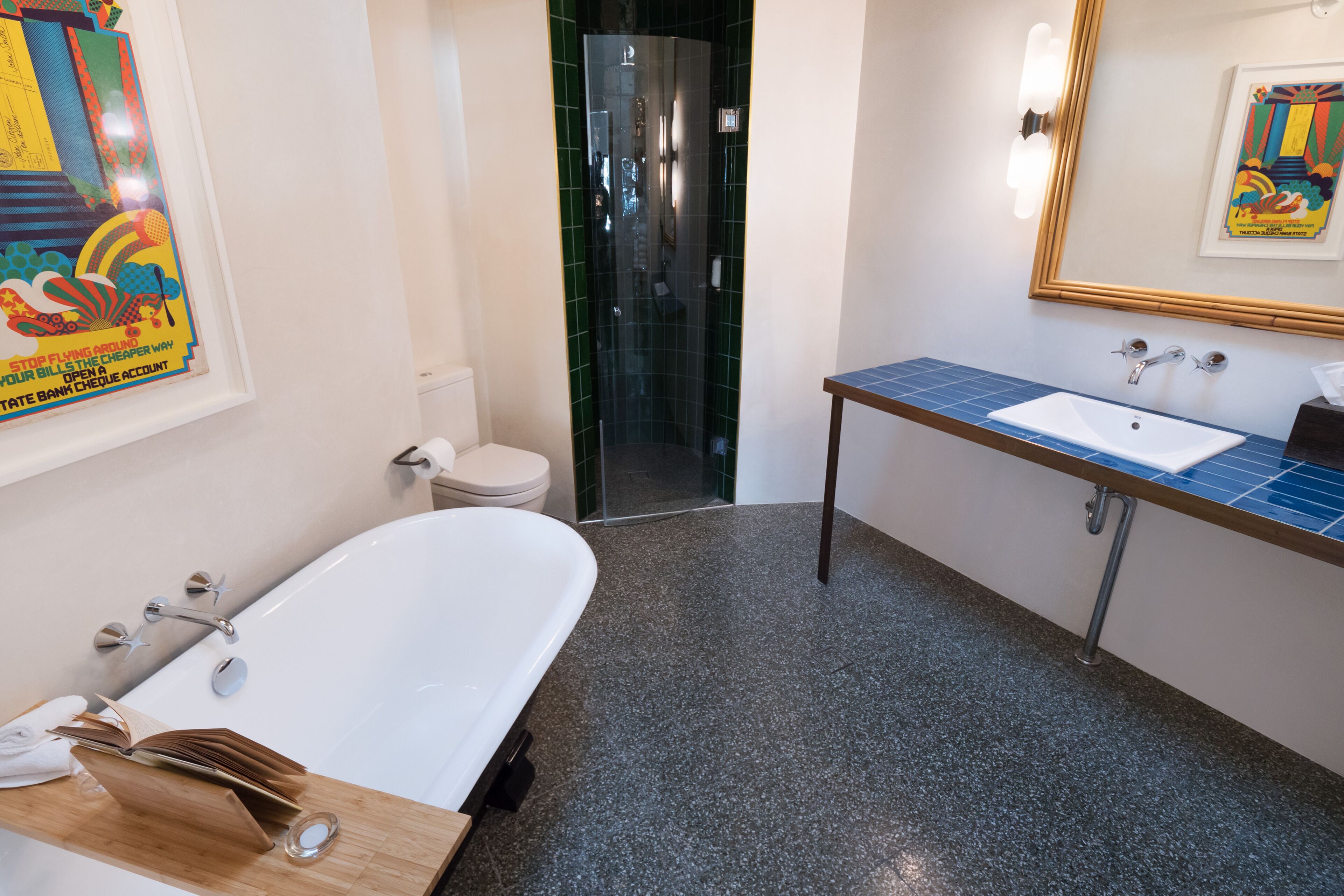Une salle de bain moderne avec une baignoire blanche, un lavabo doté d’un plan de toilette bleu et une cabine de douche en verre.