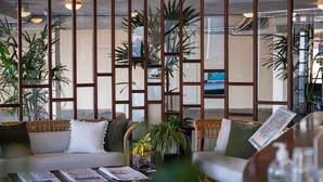 A modern living room with a sofa, chairs, a coffee table, and potted plants. - Beach Hotel Resort (Byron Bay)
