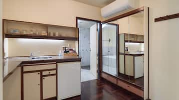 Cocina compacta con lavavajillas integrado, un espejo grande y una puerta de ducha de vidrio.