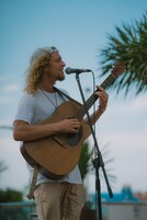Una persona tocando la guitarra en un escenario con un atril para micrófono.
