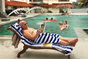 Una piscina al aire libre, sombrillas, sillones reclinables de piscina