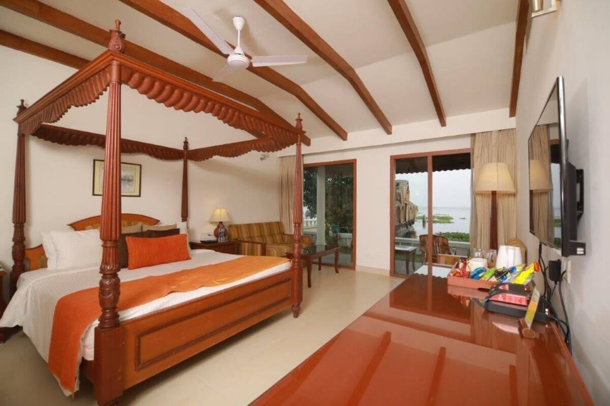 A four-poster bed, a ceiling fan, a television, and a balcony with a view.
