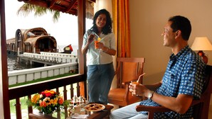 A man and a woman in a room with a view of a water body and a boat. - Lemon Tree Vembanad Lake Resort, Kerala (Cherthala)