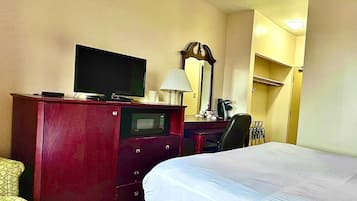 Une chambre d’hôtel comprenant un lit, un bureau avec une télévision, une lampe et un miroir.