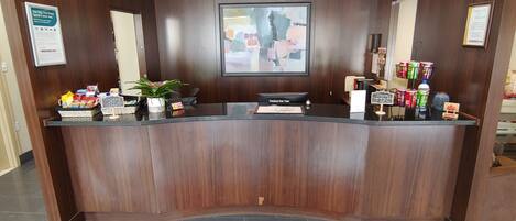 A reception desk with a digital screen, a checkout counter, and a red carpet with the logo "EconoLodge KINGSTON".