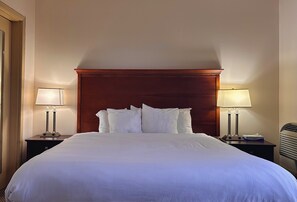 A hotel room with a large bed, two bedside tables with lamps, and a wooden headboard. - Econo Lodge City Centre (Kingston)