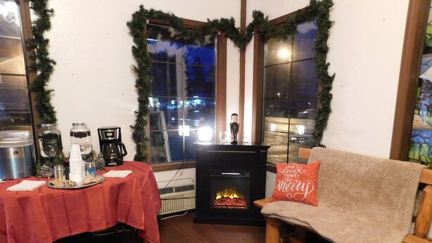 A cozy living room with a fireplace, a table with drinks, and a couch with a festive pillow. - Packwood Inn (Packwood)