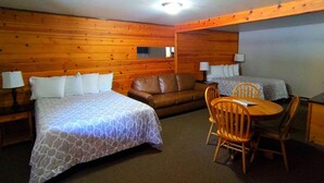 A room with two beds, a sofa, a dining table with chairs, and a television. - Packwood Inn (Packwood)