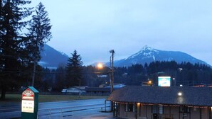 A building with a signboard, a parking lot, and a mountain in the background. - Packwood Inn (Packwood)