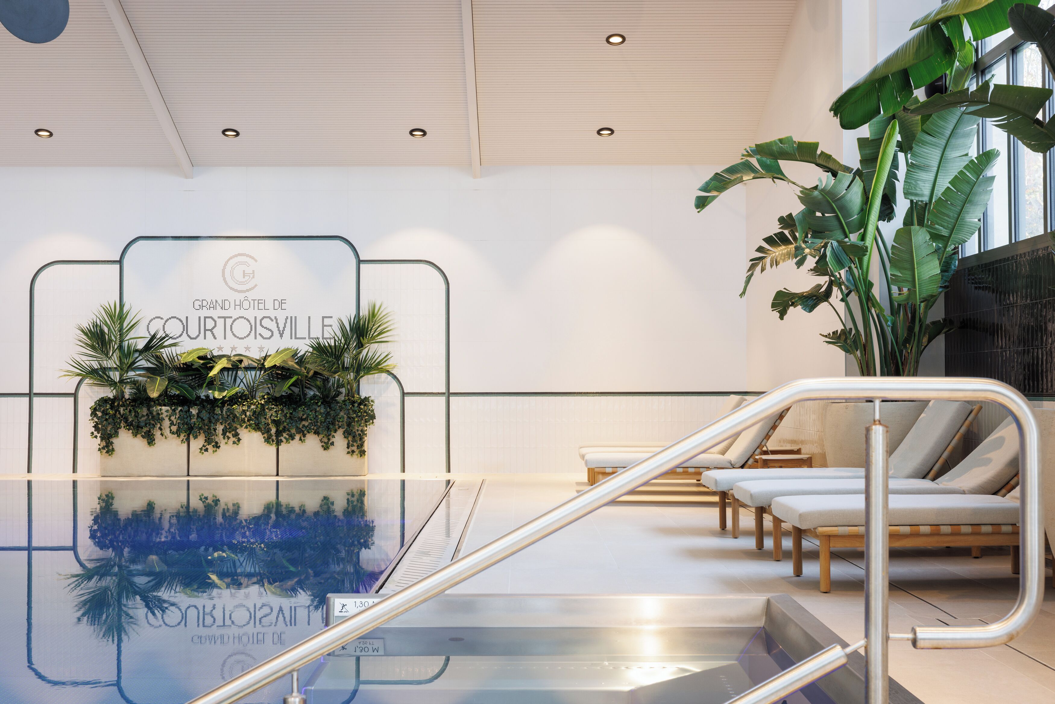 A hotel reception area with a glass wall, reception desk, and lounge chairs.