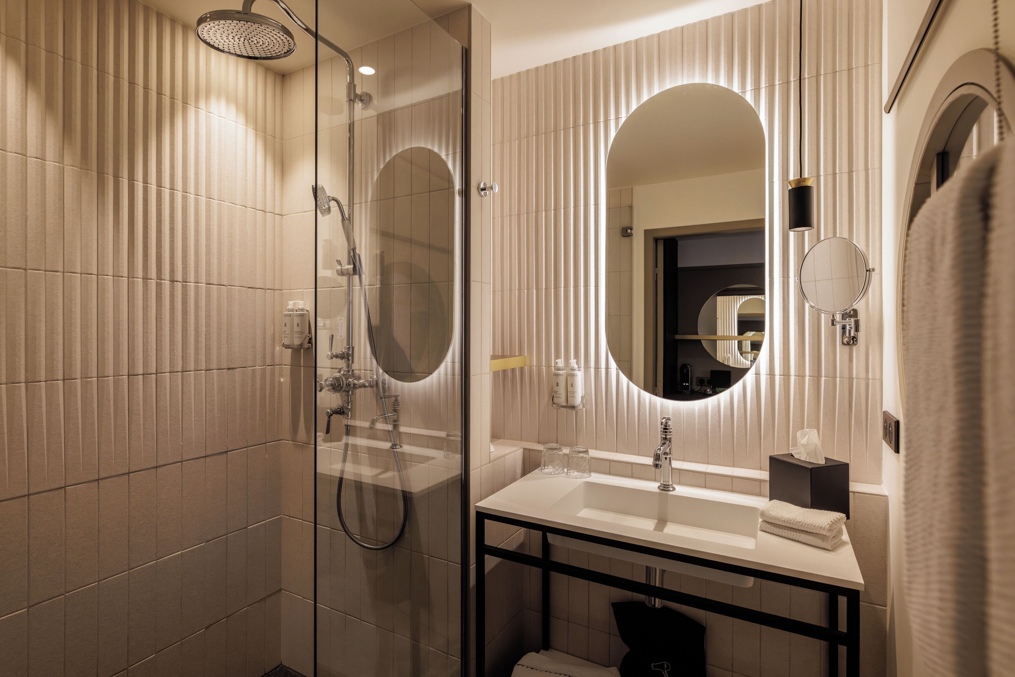 A modern bathroom with a glass-enclosed shower, a white sink, and a large mirror.