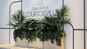 A pool area with a sign for 'Grand Hôtel de Courtoisville' and a planter with greenery. - Grand Hôtel de Courtoisville (Saint-Malo)