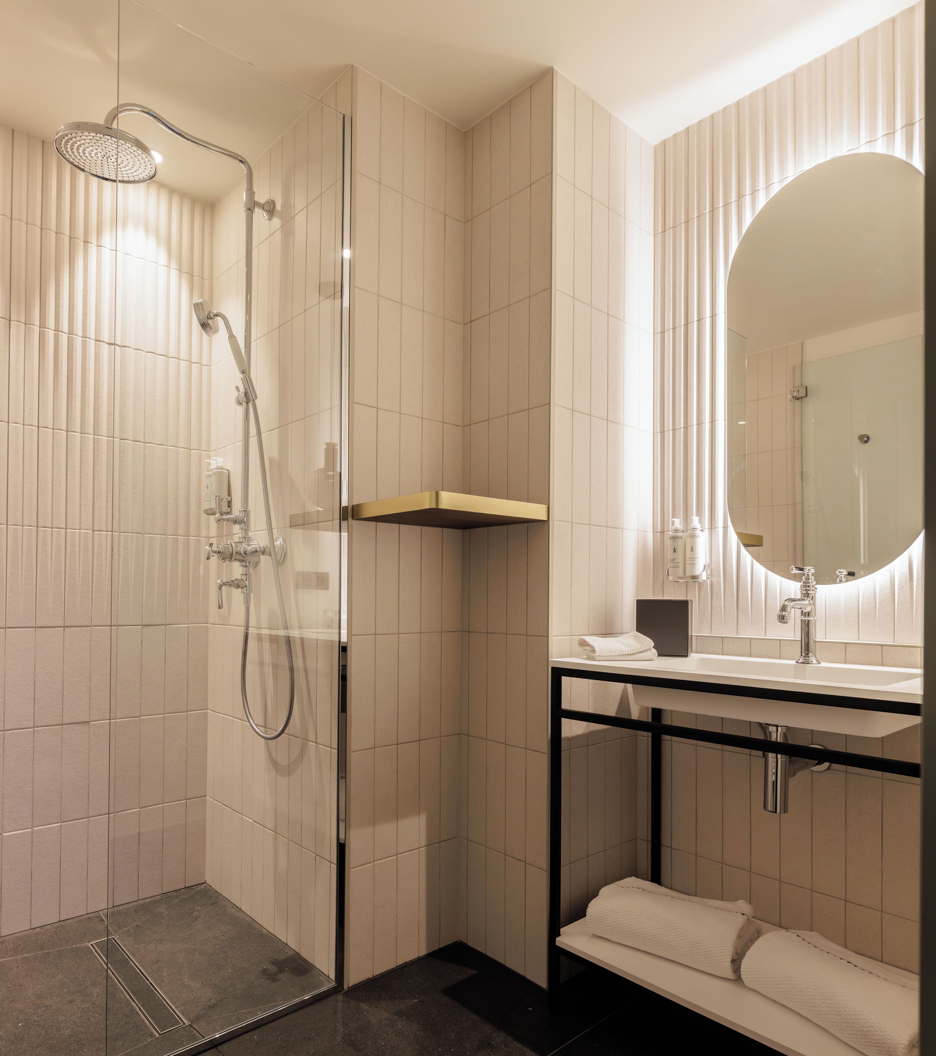 A modern bathroom with a glass-enclosed shower, a vanity with a mirror, and a towel rack.