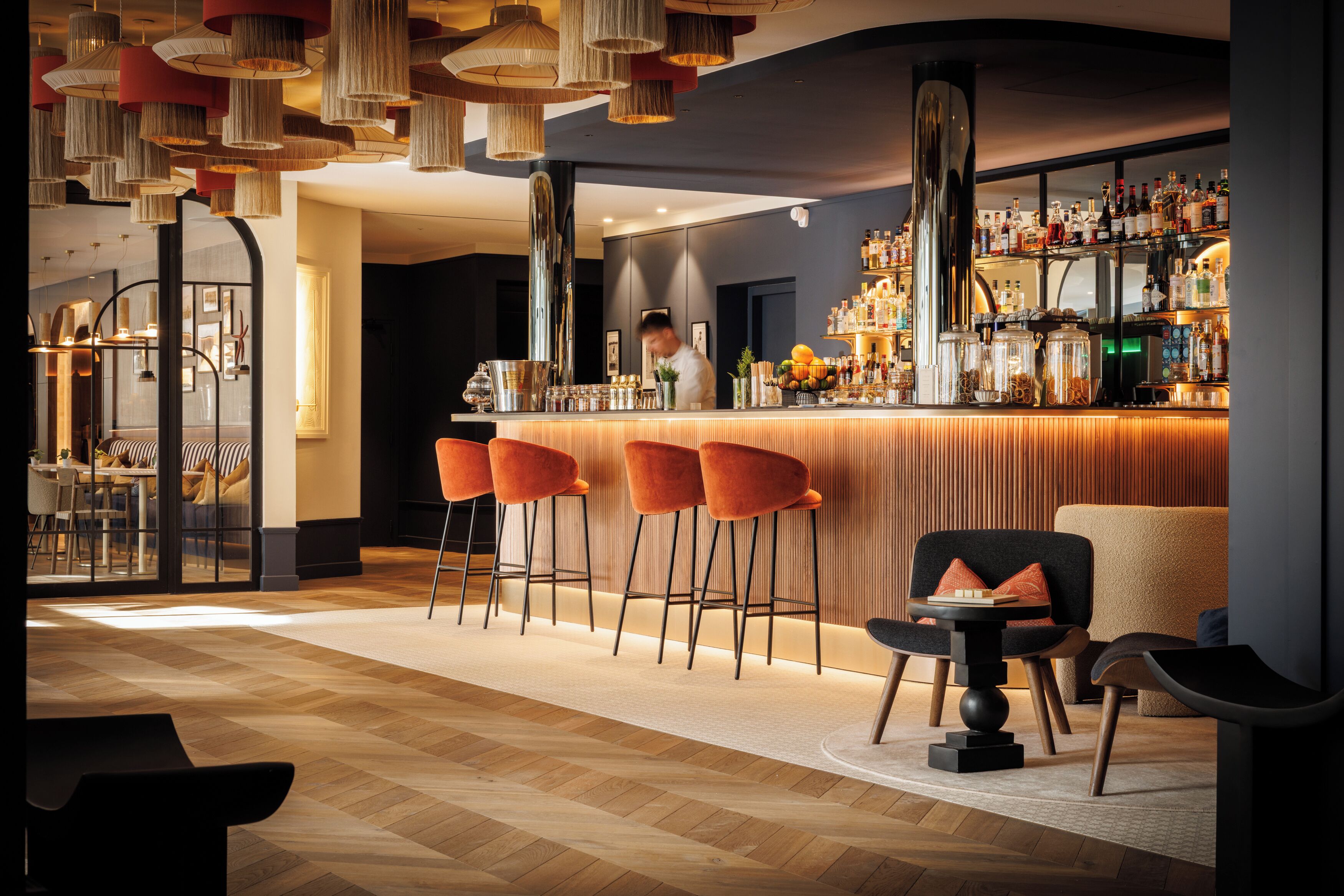 A bar area with stools, a counter, and a bartender.