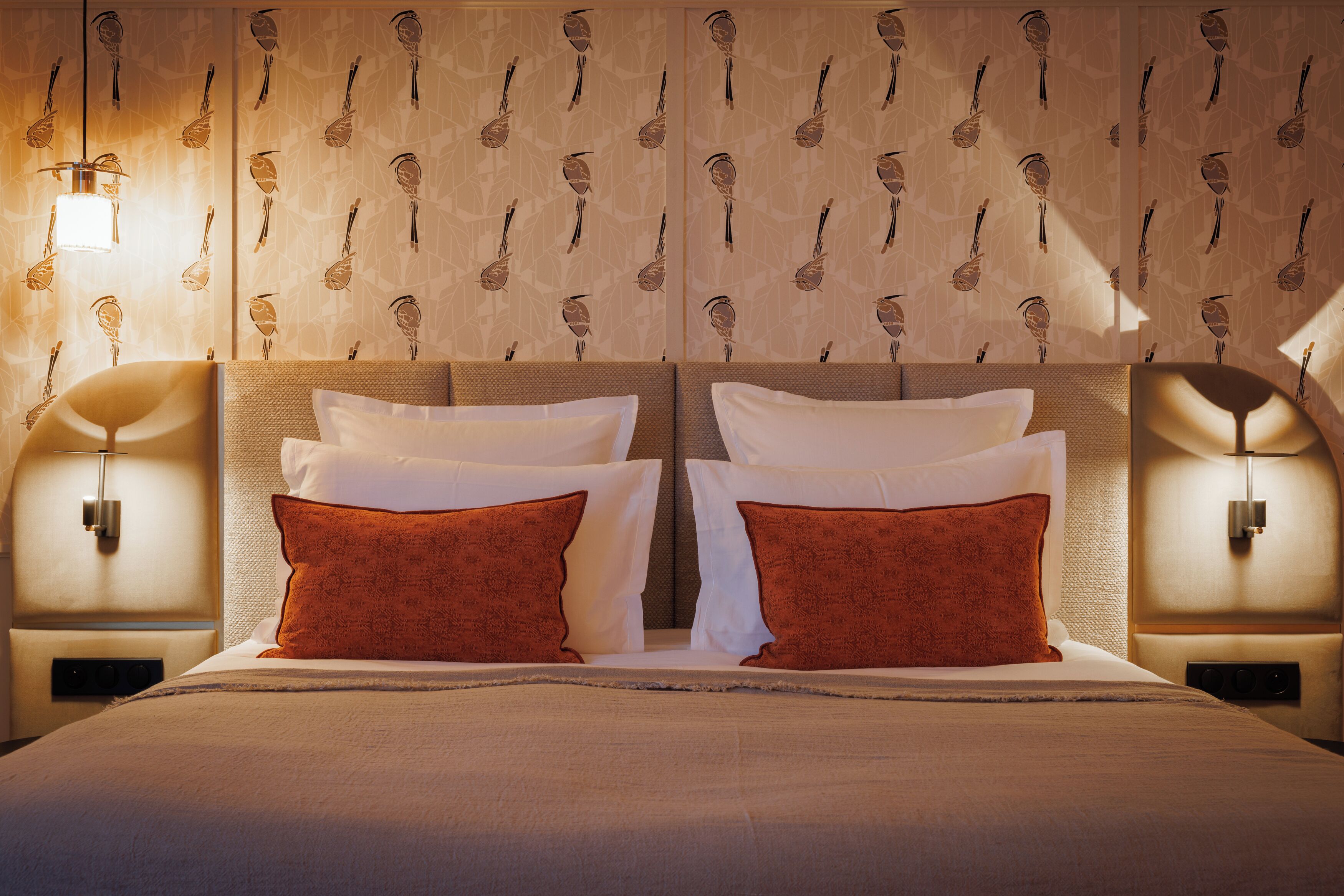 A hotel room with a large bed, two nightstands, and wall-mounted lamps.