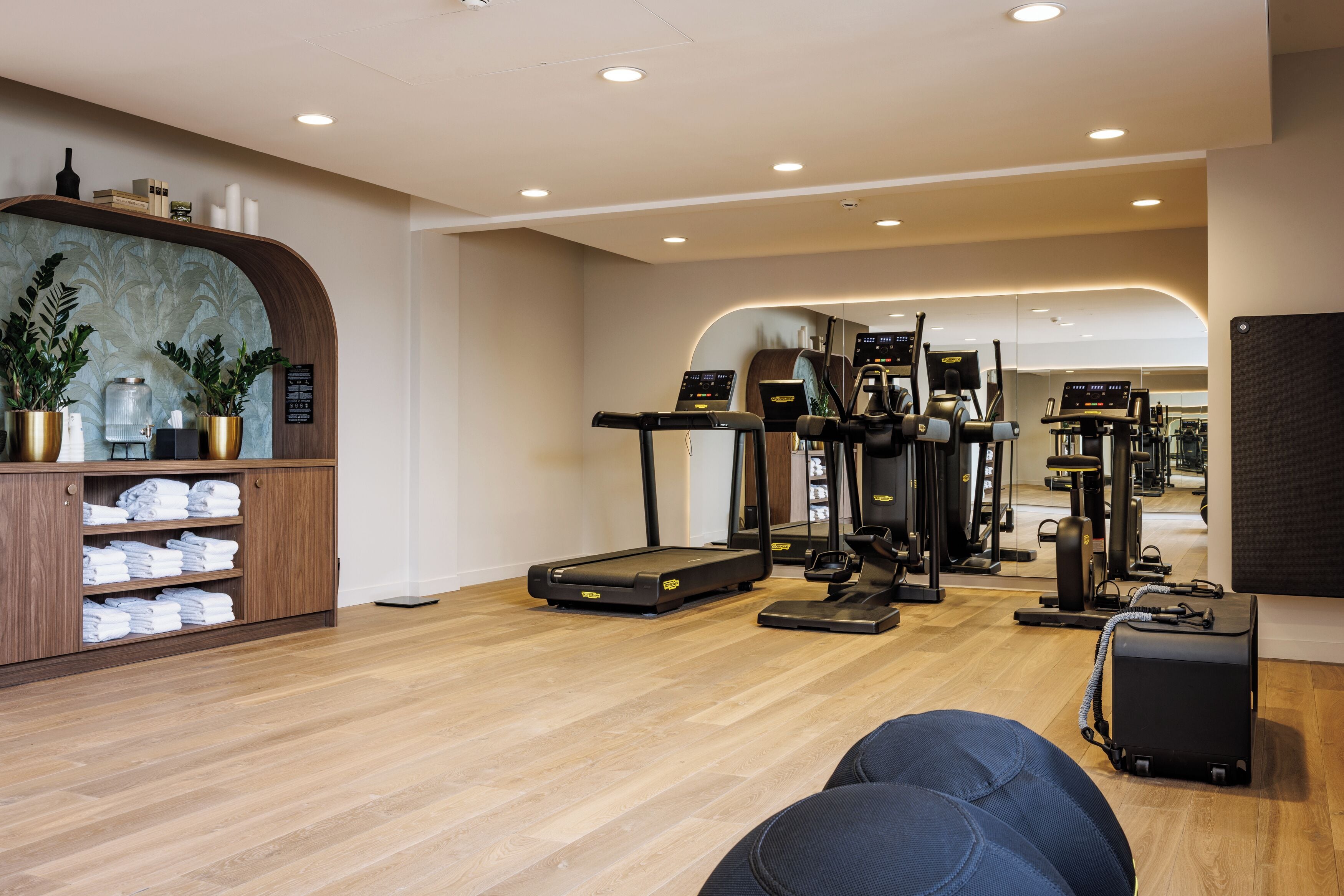A gym with exercise equipment, a treadmill, and a mirrored wall.