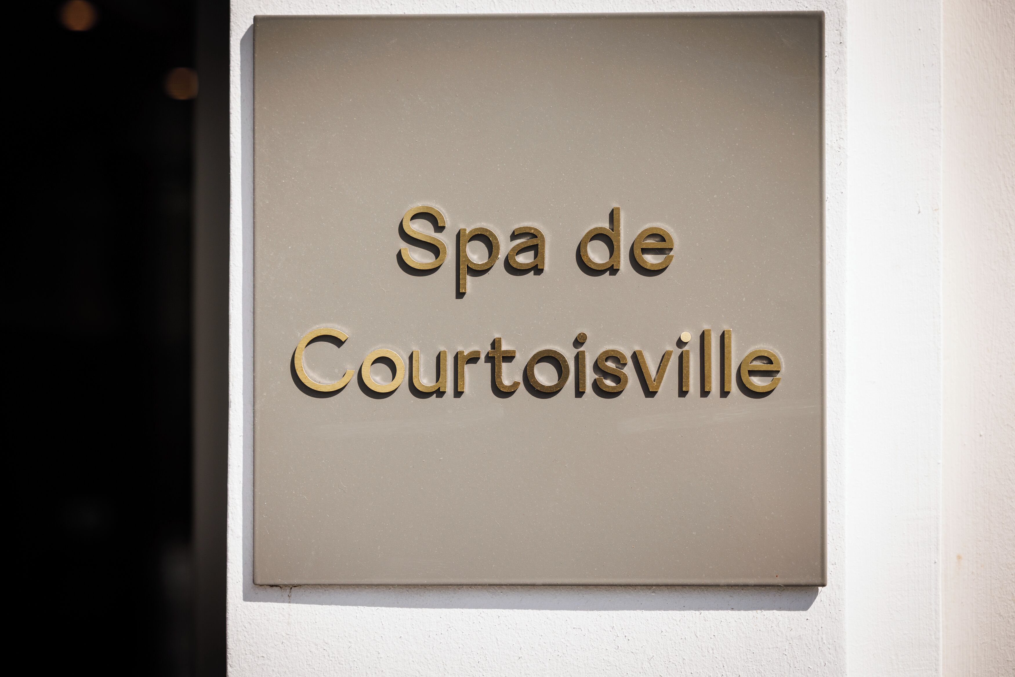 Un cartel con el texto 'Spa de Courtoisville' fijado a una pared.