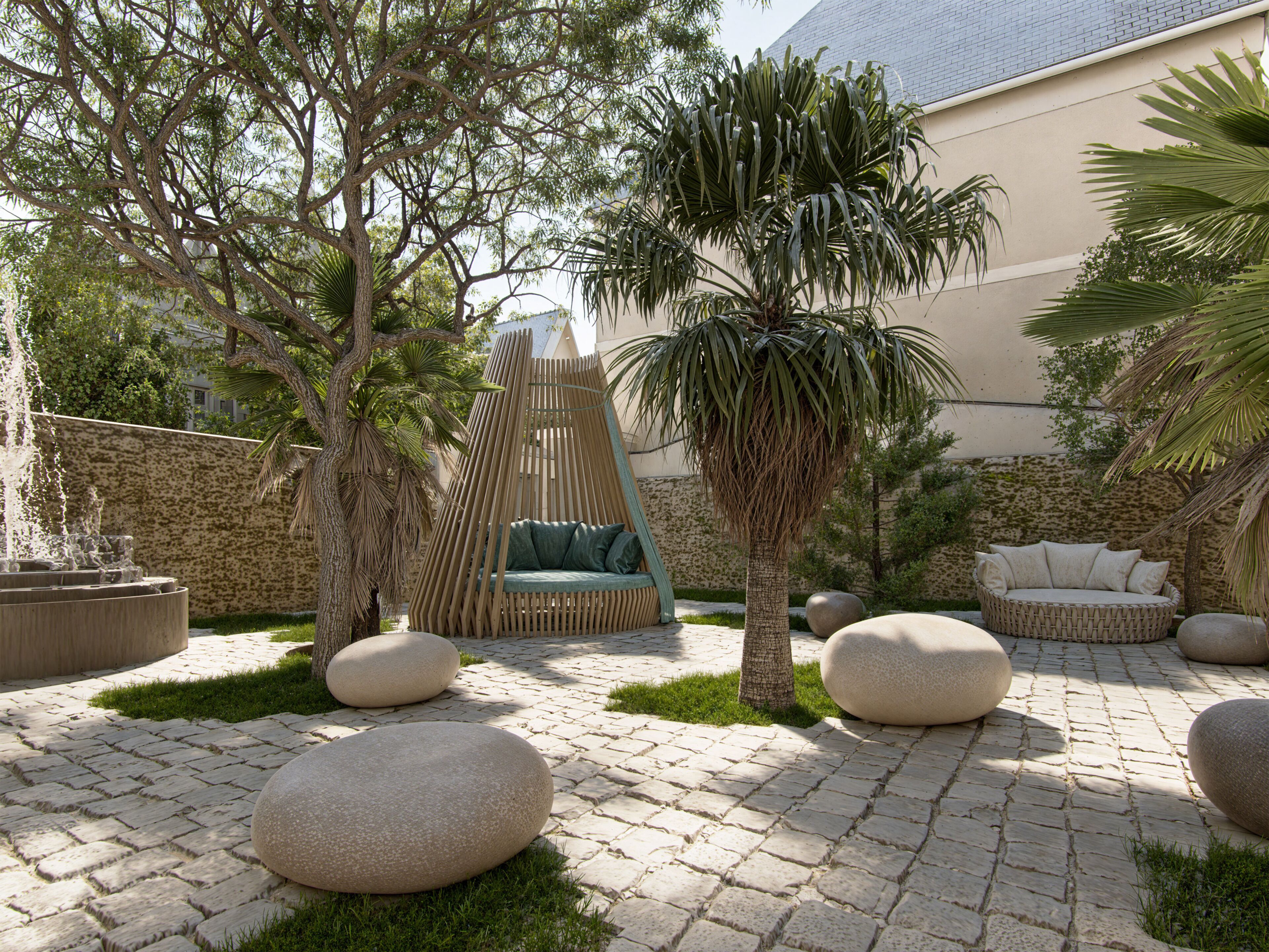 A courtyard with a seating area, palm trees, and stone planters.