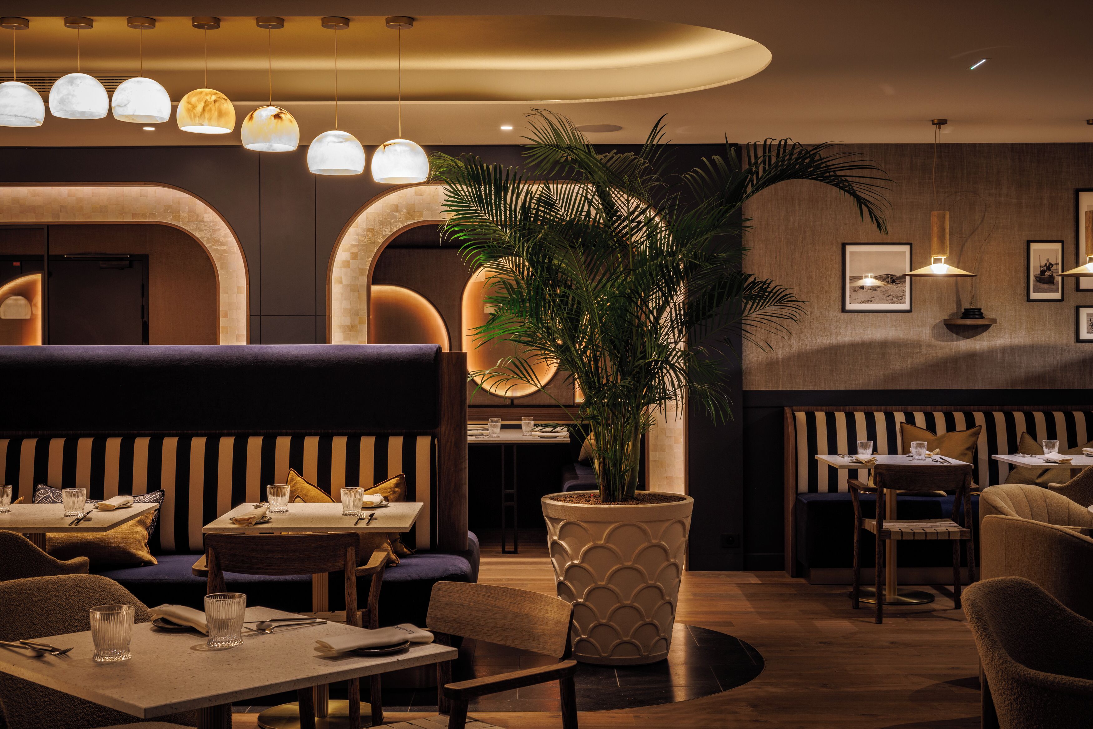 Ein Restaurant mit Tischen, Stühlen und einem großen Topfpflanzen-Dekor.
