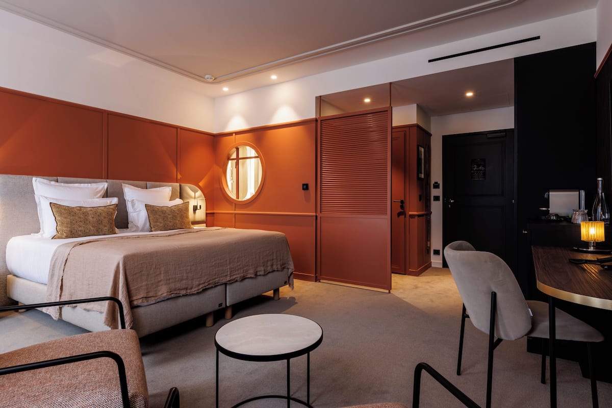 A modern hotel room with a large bed, a round table, and a seating area.