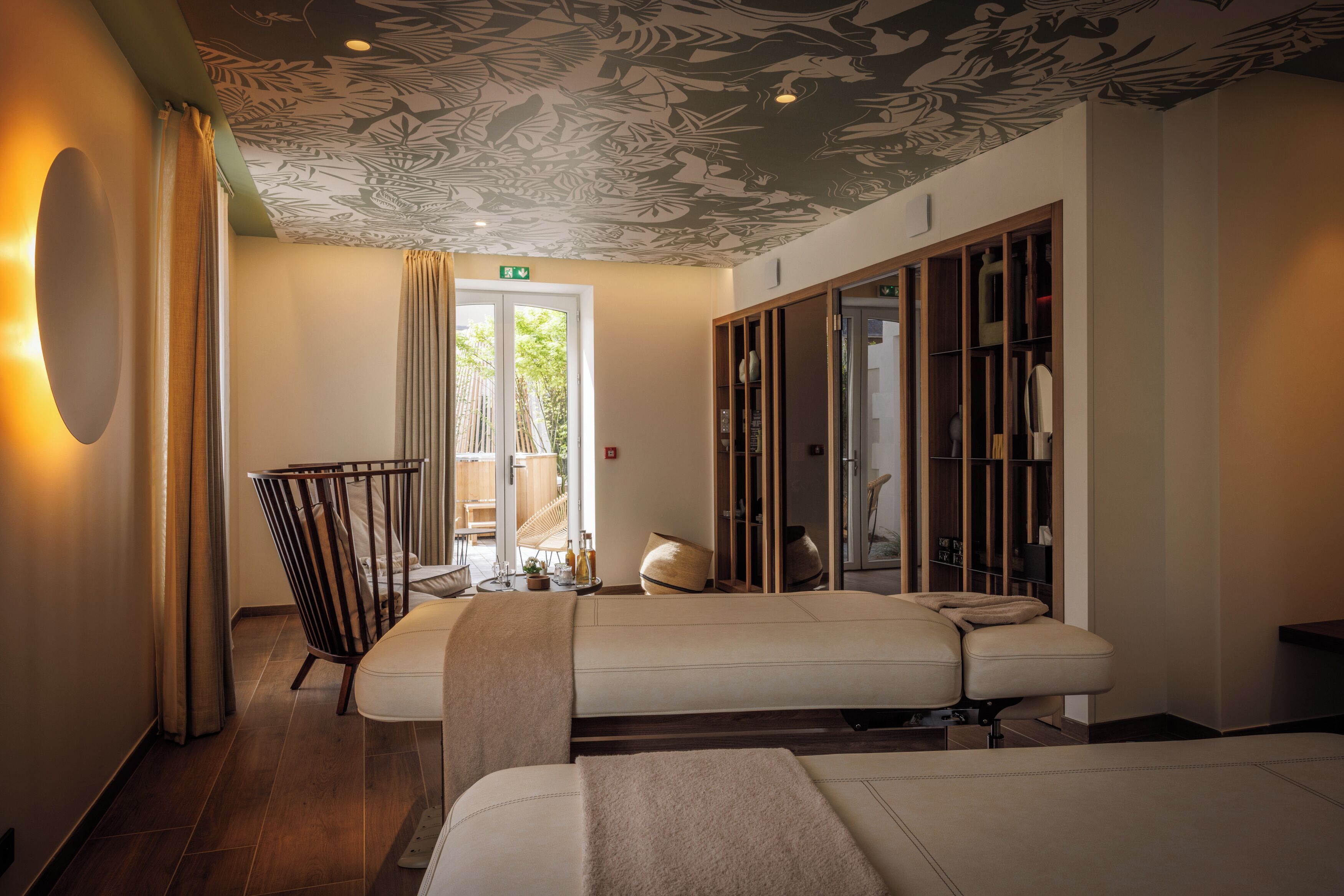 Um espaço de spa com mesa de massagem, uma cadeira de madeira e um espelho grande.