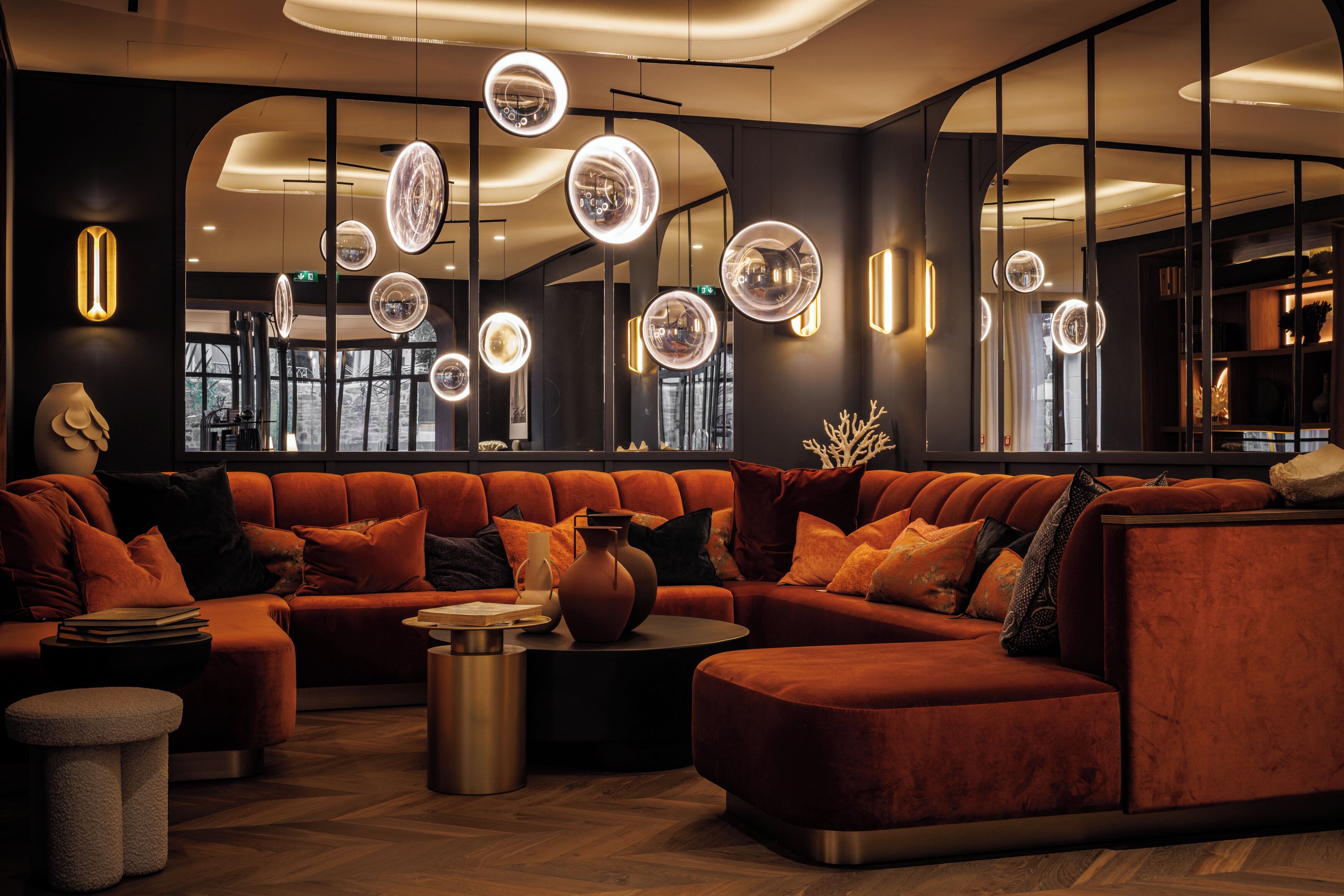 A modern interior with a sectional sofa, round mirrors, and a coffee table.