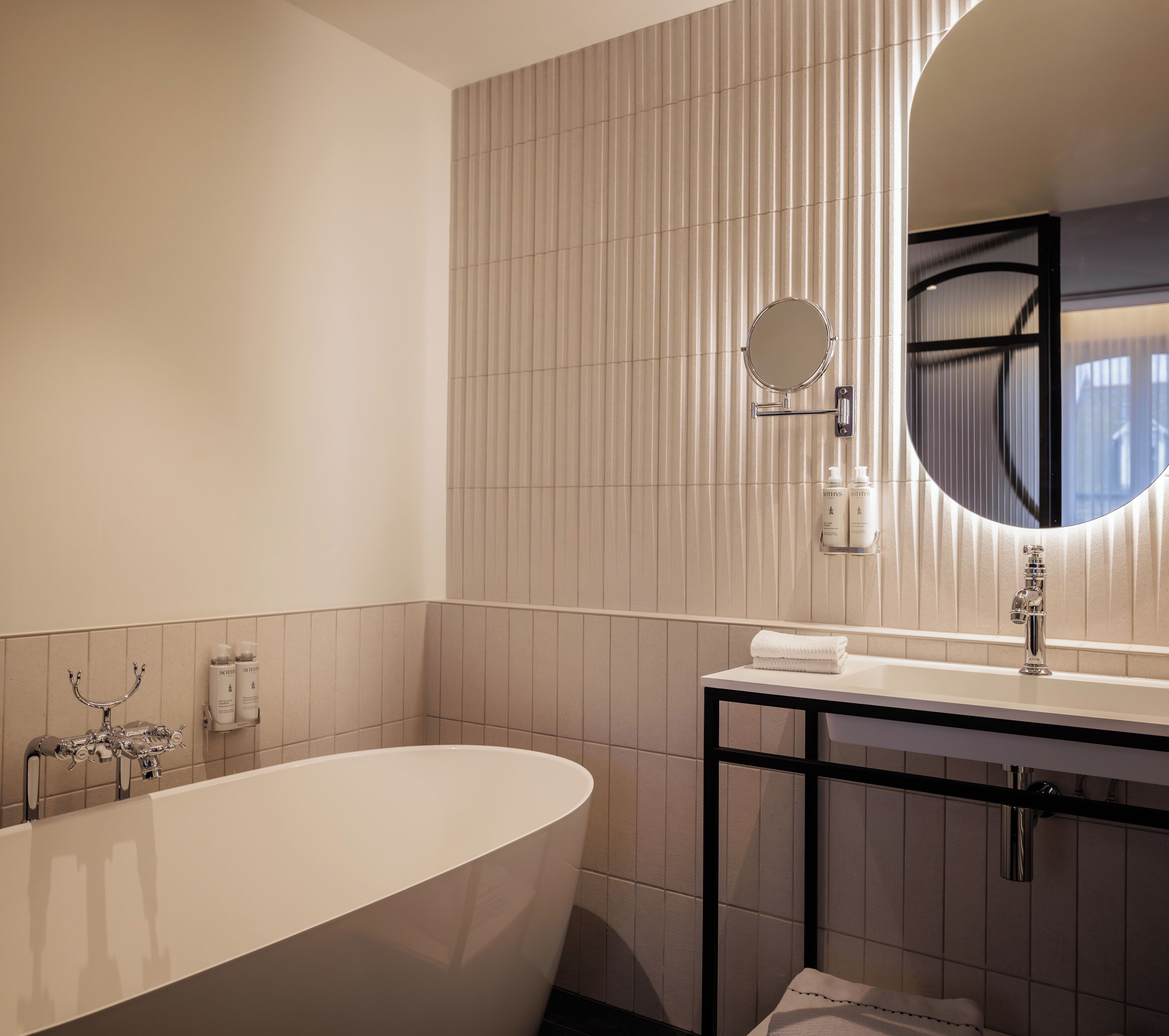 A modern bathroom with a freestanding bathtub, a round mirror, and a white sink.