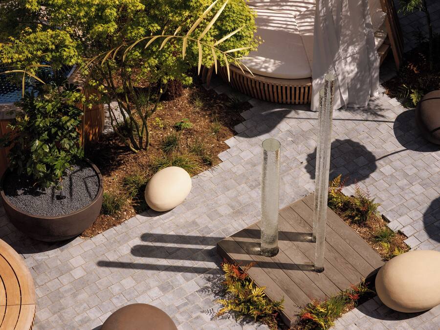 Uma área de jardim com plantas em vasos, um deck de madeira e um espaço para sentar.