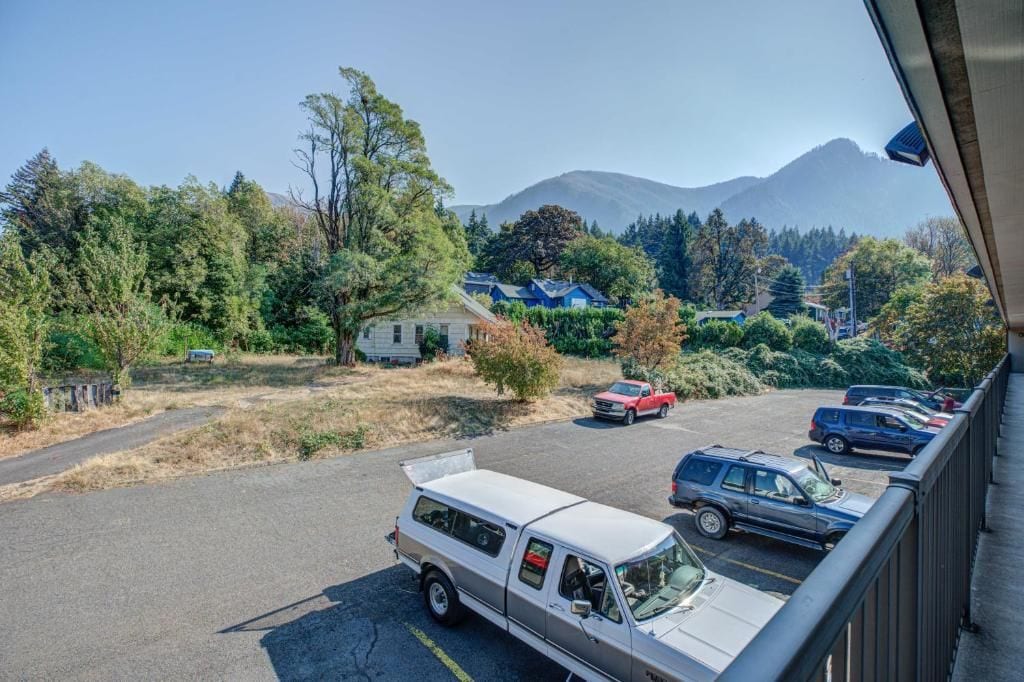 A parking lot with vehicles, a white van, and a mountain in the background.