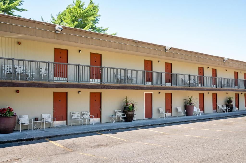 Un motel à deux étages, avec une rangée de chambres à chaque étage, des espaces de repos extérieurs et un parking.