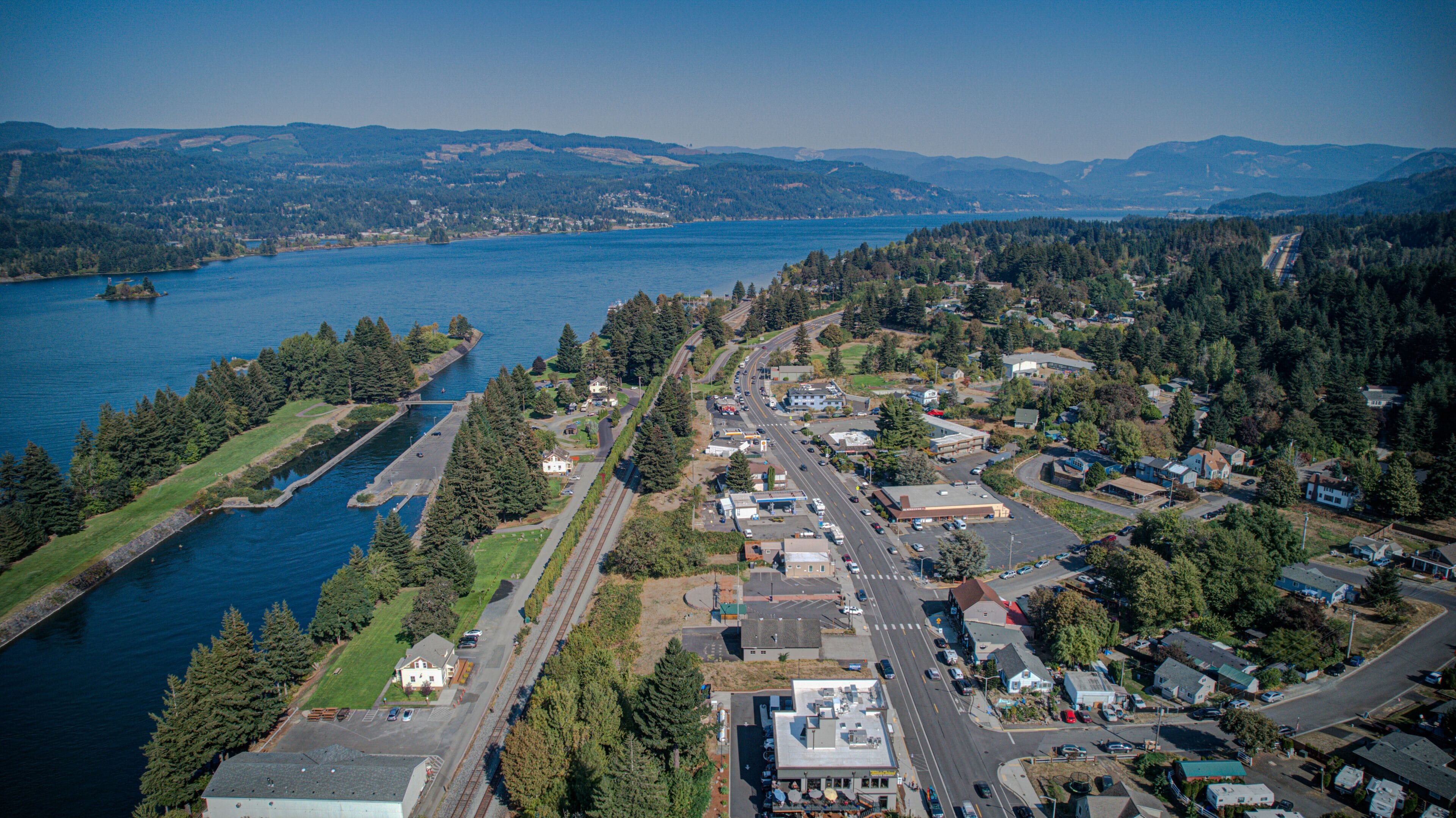 An aerial view of a coastal town with a marina, roads, and residential areas.