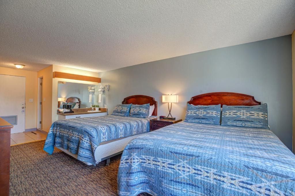 A hotel room with two beds, a mirror, bedside lamps, and a carpeted floor.