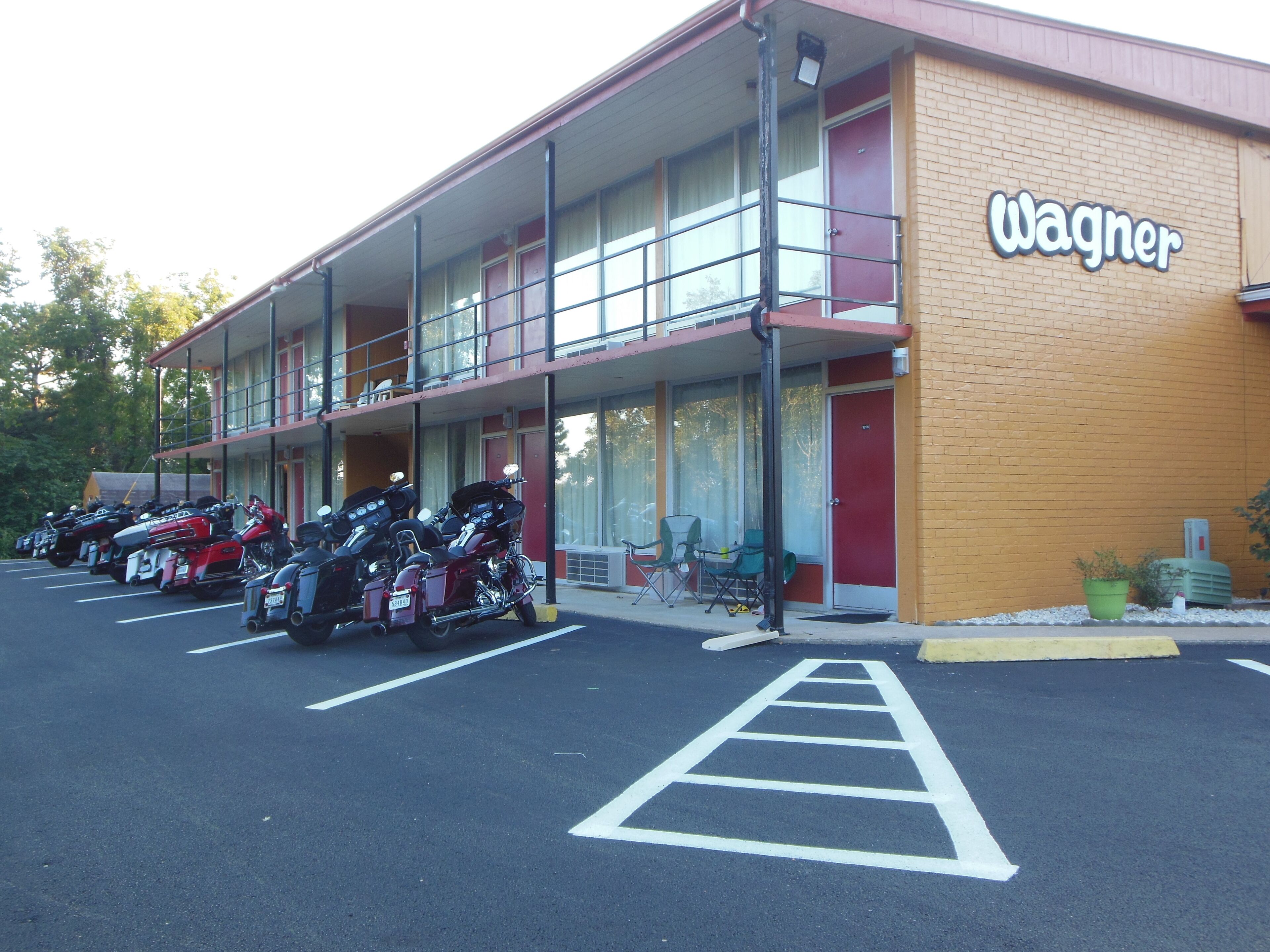 A motel with a red exterior and a sign reading "Wagner". There are several motorcycles parked in front.