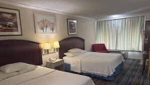 A hotel room with two beds, a red chair, a nightstand with a phone, and a window with curtains. - Wagner Inn (Eureka Springs)
