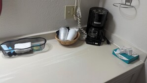 A kitchenette with a coffee maker, a basket with toiletries, a tissue box, and a power outlet. - Wagner Inn (Eureka Springs)