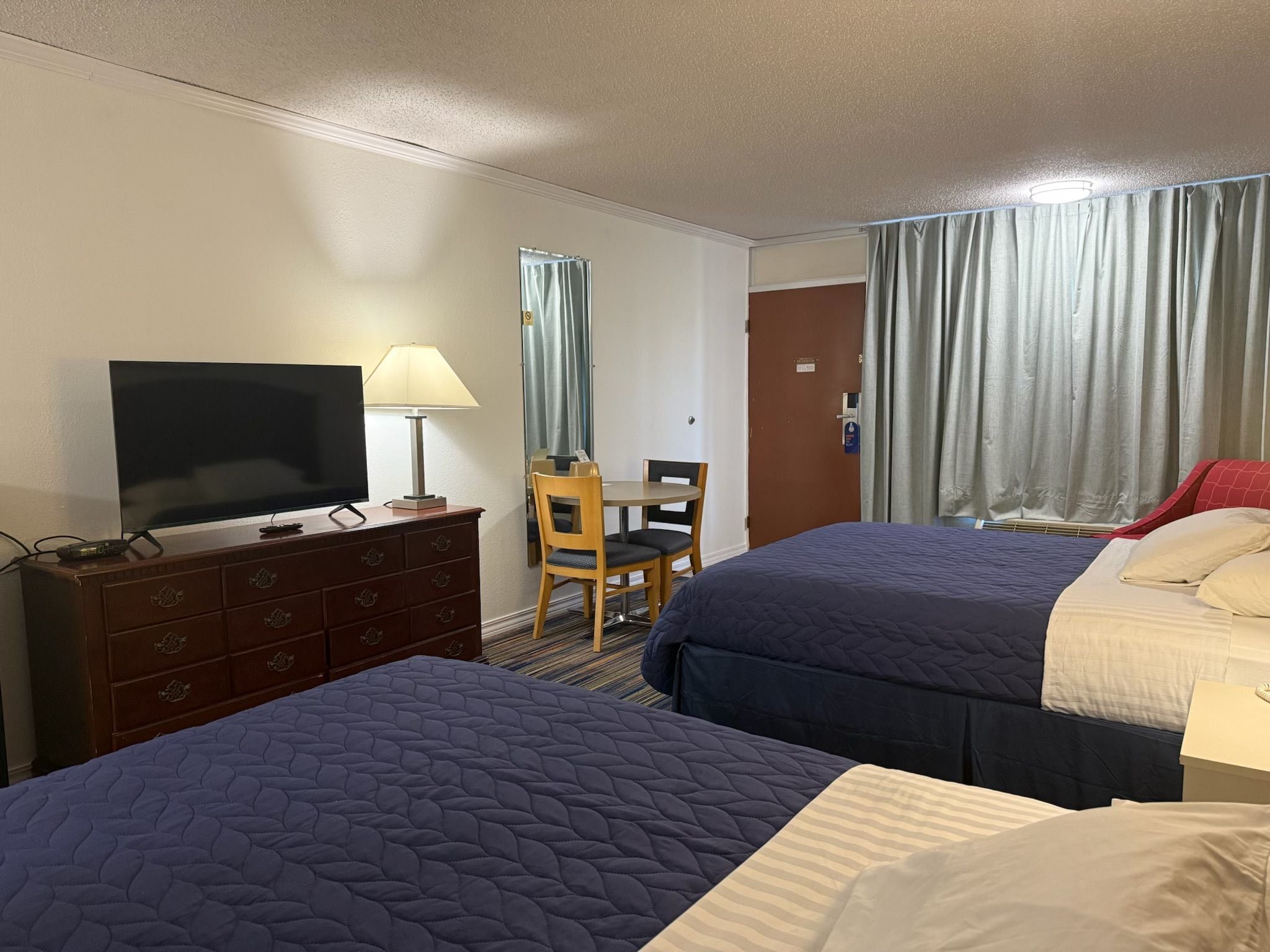 A hotel room with two beds, a TV, a desk, and a chair.
