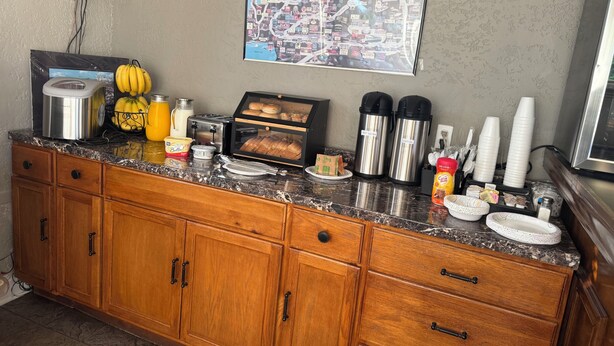 A kitchen counter with a toaster, bananas, butter, a bread display, coffee makers, and a map on the wall. - Wagner Inn (Eureka Springs)