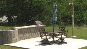 A patio with a table and chairs, a grill, and an umbrella. - Wagner Inn (Eureka Springs)