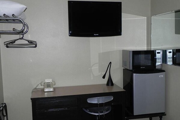 A hotel room with a desk, a flat-screen TV, a microwave, and a refrigerator. - Wagner Inn (Eureka Springs)