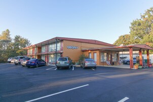 A building with a 'Wagner' sign, a parking lot with several cars, and a covered area with potted plants.