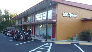 A building with a 'Wagner' sign, a parking lot with motorcycles, and a double-story structure with a balcony. - Wagner Inn (Eureka Springs)