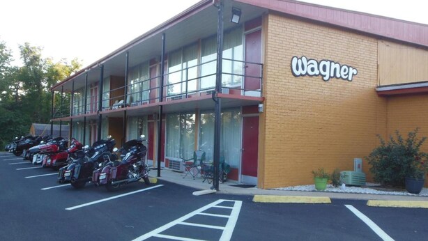 A building with a 'Wagner' sign, a parking lot with motorcycles, and a double-story structure with a balcony. - Wagner Inn (Eureka Springs)