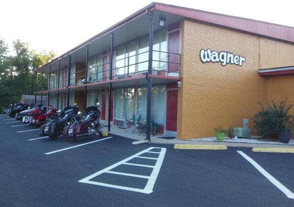 Un bâtiment portant l’inscription « Wagner », un parking où sont stationnées des motos et une structure à deux étages dotée d’un balcon.