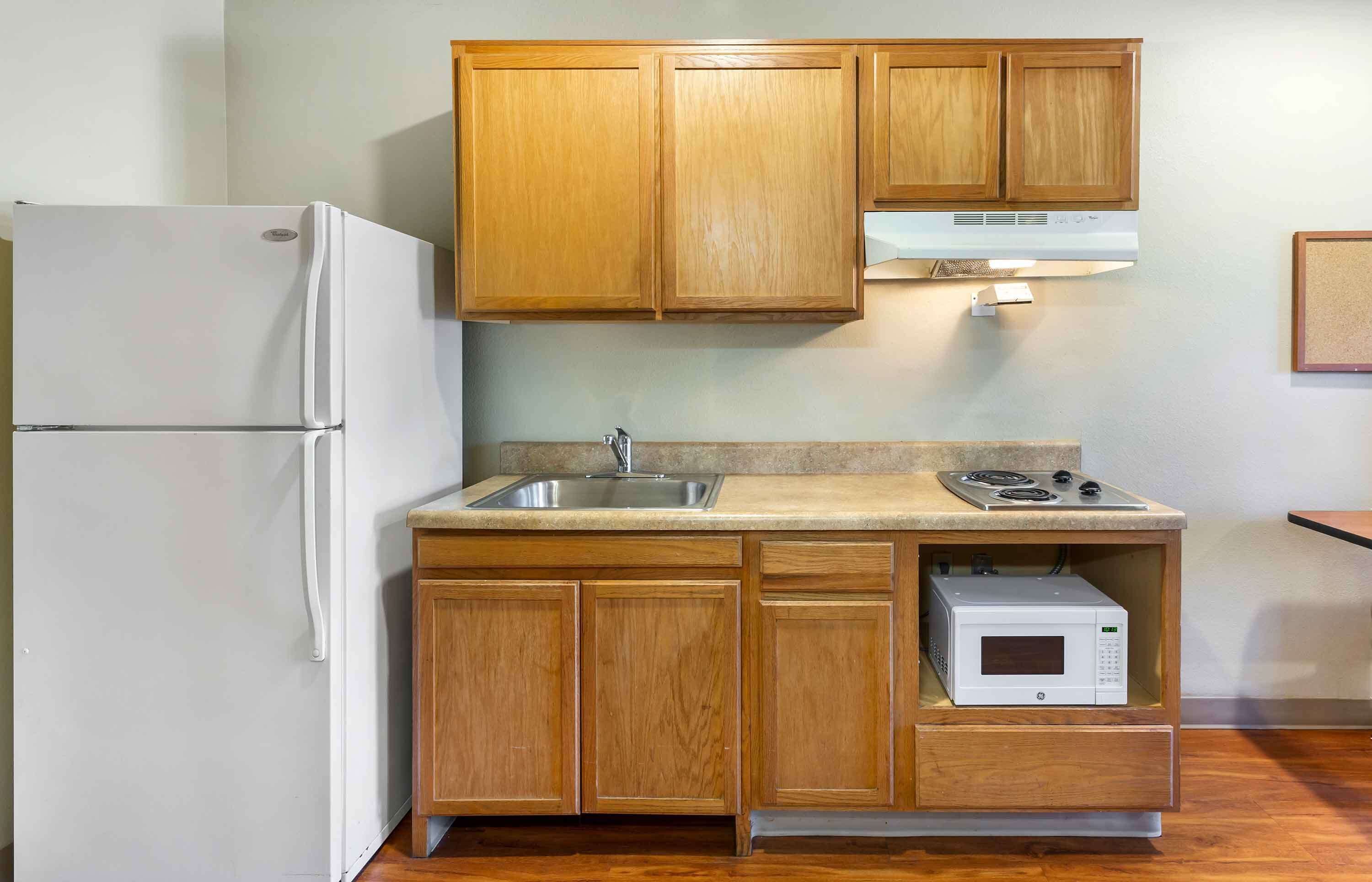 A compact kitchen with wooden cabinets, a built-in microwave, and a stainless steel sink.