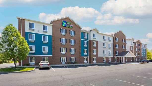 Un hotel de varios pisos con fachada de ladrillo, una decoración azul y blanca y un estacionamiento al frente.