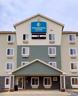 Ein mehrstöckiges Hotel mit einem Schild, auf dem "Woodspring Suites" und "Wochenpreise" stehen.